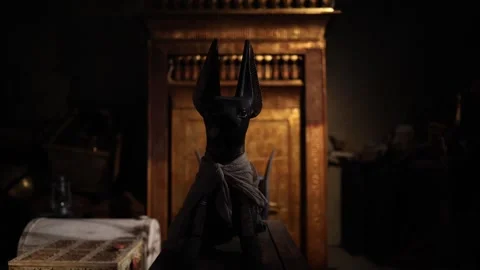 A black Anubis statue stands solemnly before a golden shrine in an ancient tomb. Stock Footage 301792030