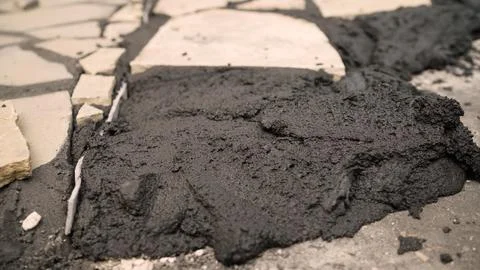 Black asphalt patch on cracked stone pavement Stockfoto's