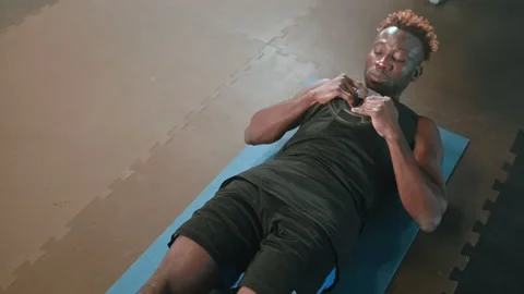 Black athlete doing abs exercise with weight plate Stock Footage 233828440