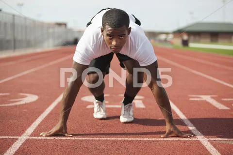 Black athlete kneeling at track starting line Stock Photos