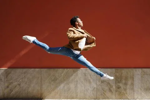 Black athletic man doing an acrobatic jump outdoors Stock Photos