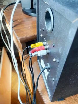 Black audio speaker with RCA input ports and connected cables on a wooden Фото