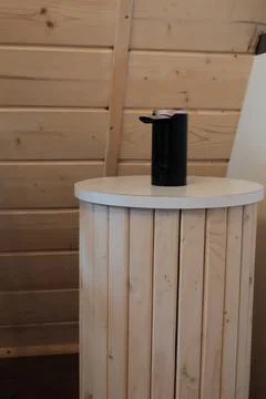 Black automatic soap dispenser resting on a wooden cylindrical pedestal stand Stock Photos