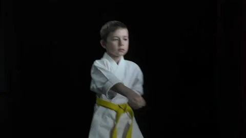 On a black background, a boy athlete performs punches Stock Footage 145071446
