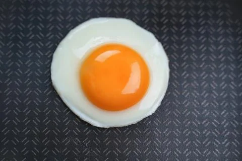 Black background. Fried egg in a pan. Top view Stock Photos