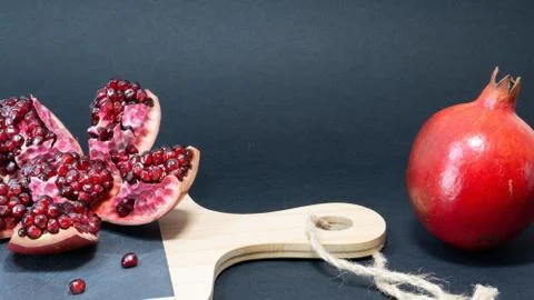 Black background, on the left of the kitchen board there is an open pomegrana Foto stock