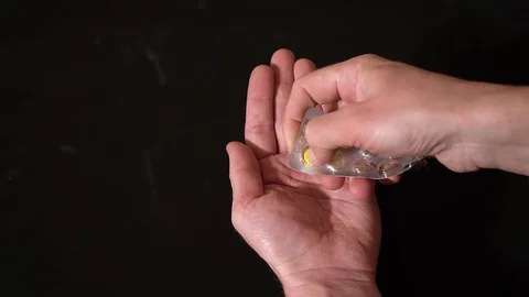 On a black background out of the blister squeezed, yellow pills in hand. Video stock 128841047