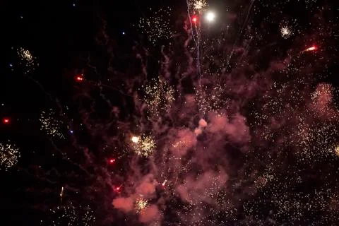 On a black background, red rays and sparks of a scattering fireworks with smo Stock Photos