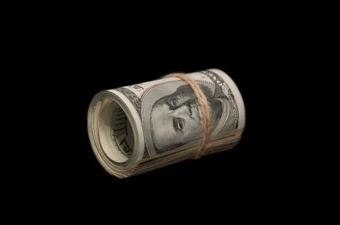 On a black background, a roll of one hundred dollar bills tied with a rope. It Stock Photos