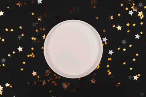 Black background with shiny stars and empty plate mock up Stock Photos