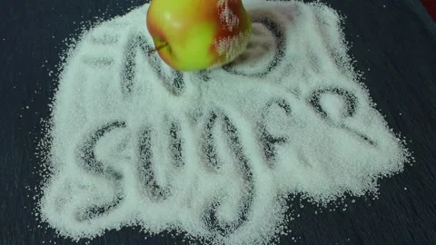 On a black background is sugar labeled “no sugar”. A green apple is rolling Stock Footage 300488629