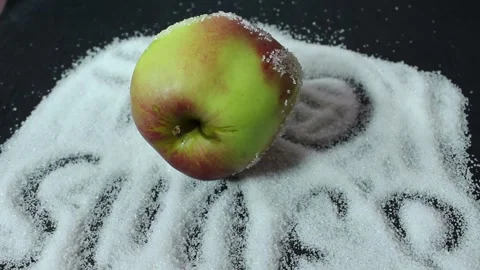 On a black background is sugar labeled “no sugar”. A green apple is rolling Stock Footage 300488631