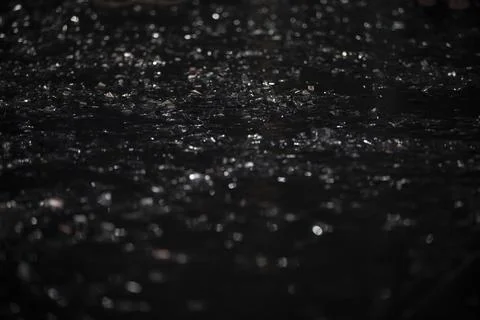 On a black background there are silver bokeh spots from shiny confetti. Stock Photos