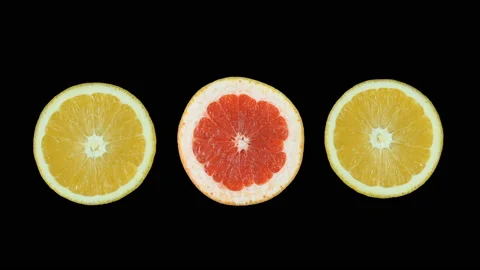 On a black background, two cut orange and one grapefruit rotate. Isolated. Stock Footage 119696869