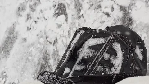 A black backpack covered in snow 스톡 동영상 270742459