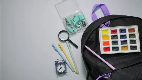 Black backpack filled of school supplies  on white background. Stop motion Stock Footage 283261097