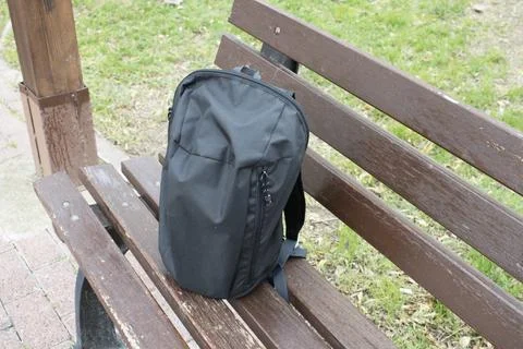 Black backpack on park bench Stock Photos