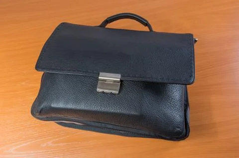 Black bag on a brown table 스톡 사진