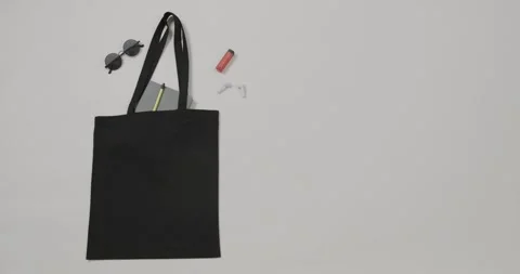 Black bag with sunglasses, notebook, lipstick on white background, copy space, Stock Footage 331295046