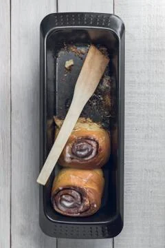 Black baking pan with two fresh homemade cinnamon rolls and a spatula Stock Photos