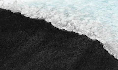 Black beach background waves black and white on volcanic sand texture washed Stock-Fotos