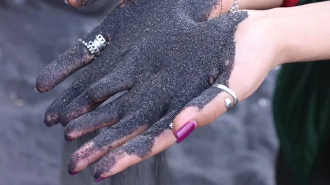 Black beach sand falling from a woman's hands Stock Footage 312989910