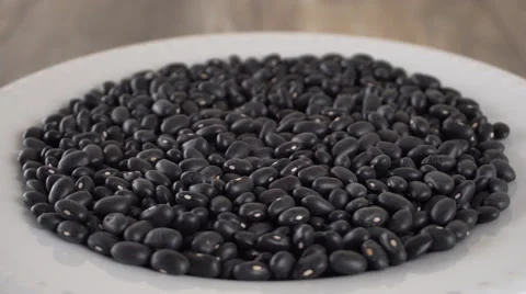 Black beans rotating on a white plate. Seamless loopable. Prores 4K Stock-Footage 67359353