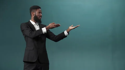 A black bearded man in a tuxedo is posing, standing with with outstretched arms Stock Footage 170668066