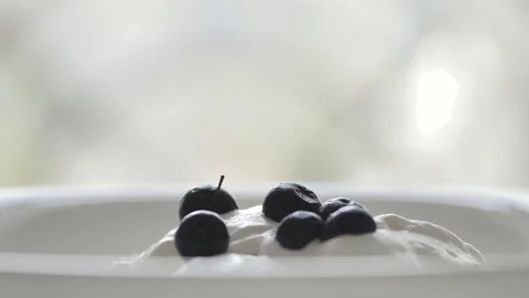 Black berries are falling on a white ice cream from above, closeup shot Stock Footage 116055452