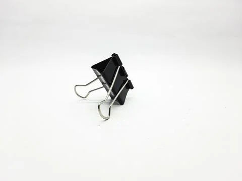 Black binder clip on a white surface used for holding papers together Stock Photos