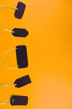 Black blank tags hanging on string against orange background Stock Photos