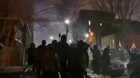 Black bloc hitting garbage during a protest at night Stock Footage 87751017