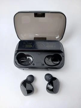 Black bluetooth earbuds and opened charging case. Stock Photos