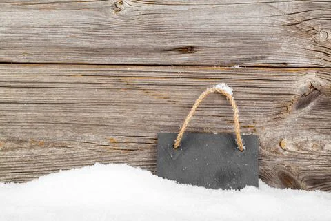 Black board of slate on old rustic wooden background, with snow Stock Photos