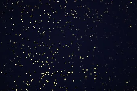 Black bokeh texture on black background. Dark background with small lights. Stock Photos