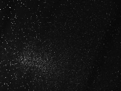 Black bokeh texture on black background. White glitter or illuminated dust Stock Photos