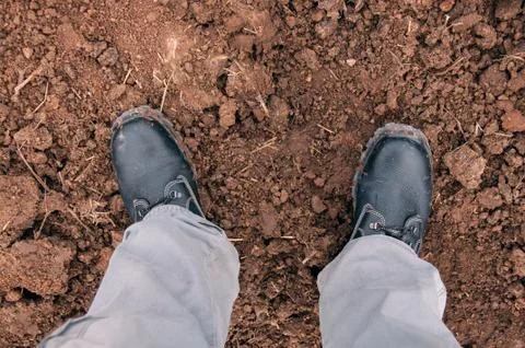 Black boots on clay soil. Work shoes Stock Photos