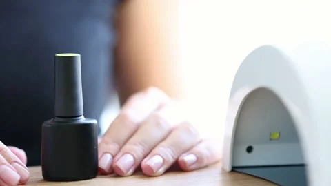 Black bottle of shellac near uv lamp with womans hands behind. Selective focus. Stock Footage 221677626