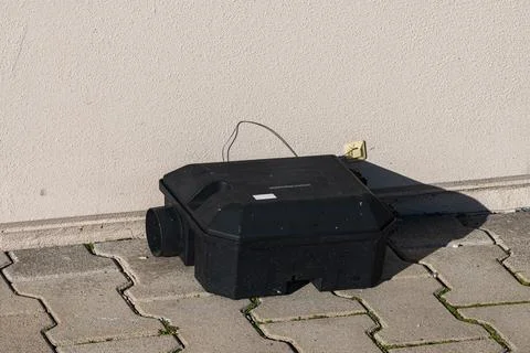 Black box next to wall with cable on pavement during daylight Stock Photos
