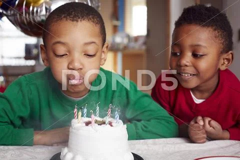 Black Boy Blowing Out Cake Candles At Party