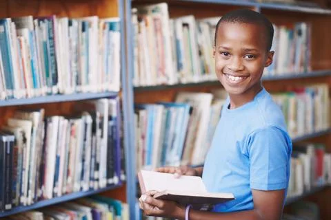 Black boy, library and smile for reading book at elementary school for literacy Stock Photos