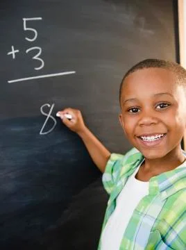 Black boy solving math problems on blackboard Stockfoto's