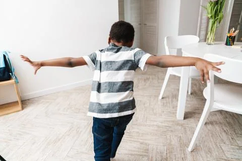 Black boy in t-shirt running and making fun at home Stock Photos