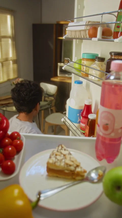 Black Boy Taking Slice of Cake and Juice Bottle from Refrigerator Stock Footage 342256627