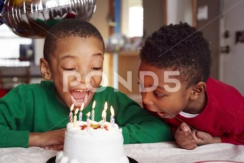Black Boys Blowing Out Cake Candles At Party