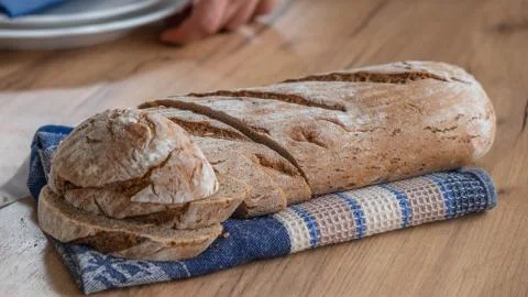Black bread made of integral flour on a blue cloth on a table Stock Photos