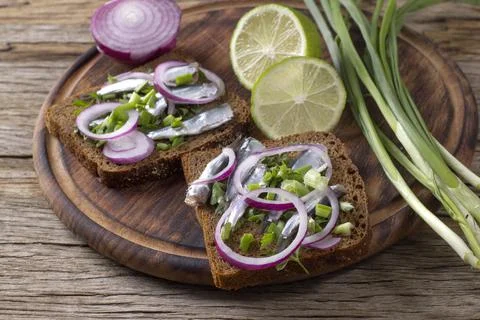 Black bread sandwiches with salted sprat carcasses with onions and parsley Stock Photos