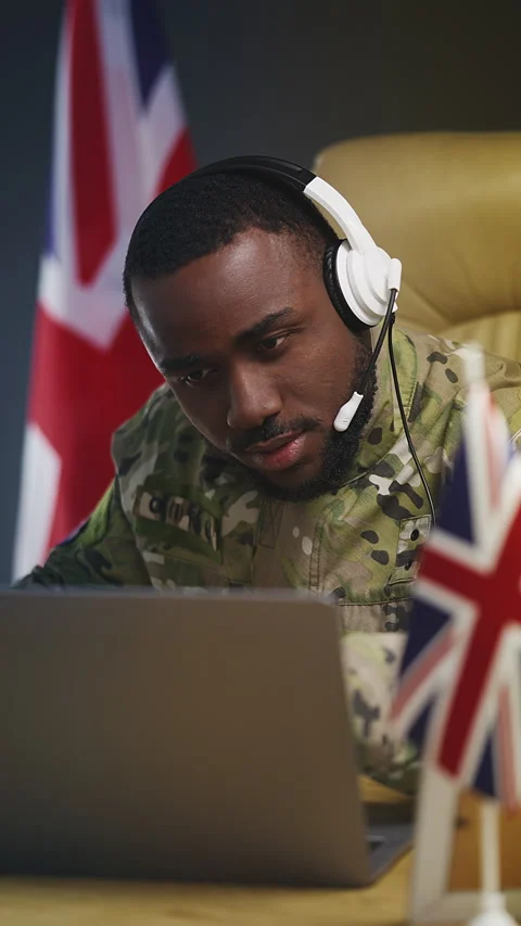 Black British army officer in headset controls military operation in office Stock Footage 346640498