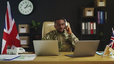 Black British serviceman in headset supervises military operations on laptops Stock Footage 342149076