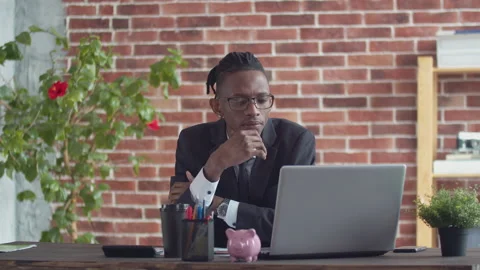 Black brooding man in glasses and a strict suit looks at the laptop screen at Stock Footage 162834278